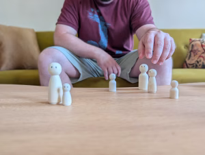 Eine Hand stellt Figuren in einer Familienaufstellung auf