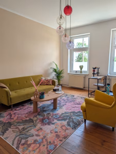 Blick auf den Therapieraum mit Couch, Sessel und Couchtisch
